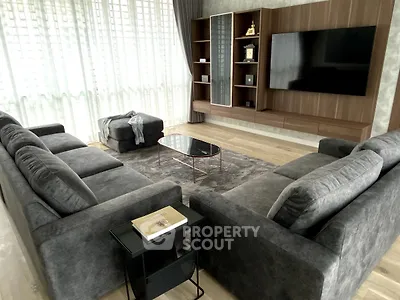 Luxurious living room with plush gray sofas, modern entertainment center, and floor-to-ceiling windows.