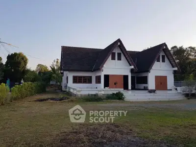 Charming countryside house with unique triangular roof design and spacious front yard.