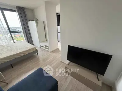 Modern studio apartment with city view, featuring a cozy living area and sleek furnishings.