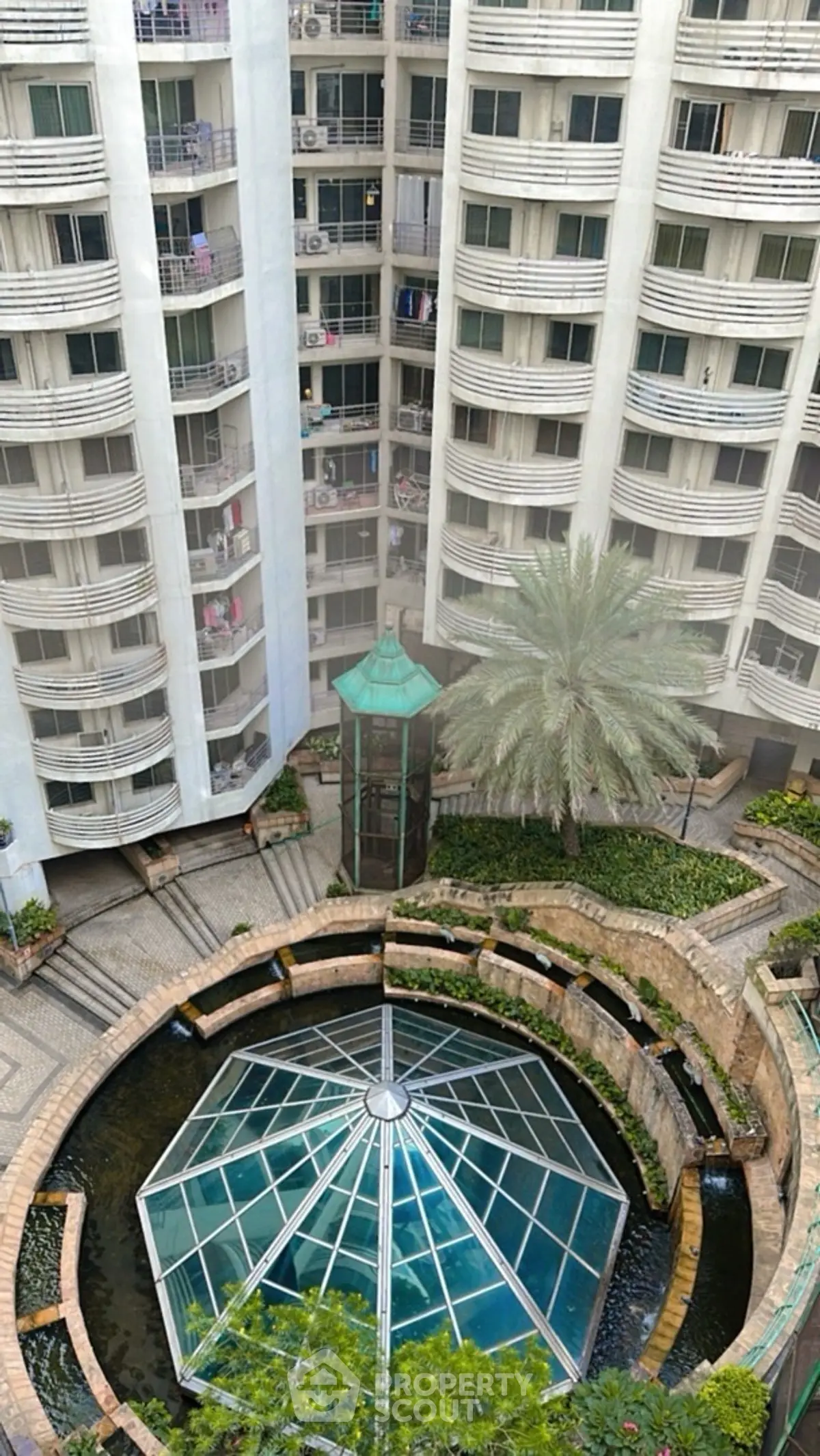 Stunning view of modern apartment complex with unique glass dome and lush landscaping.
