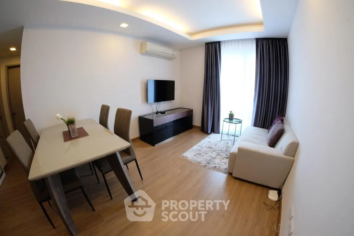 Modern living room with elegant dining area and cozy seating, featuring sleek furniture and ambient lighting.