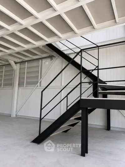 Modern industrial-style staircase in a spacious open-plan interior with high ceilings.