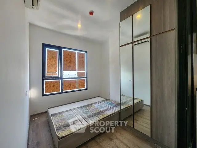 Modern minimalist bedroom with large mirrored wardrobe and natural light.