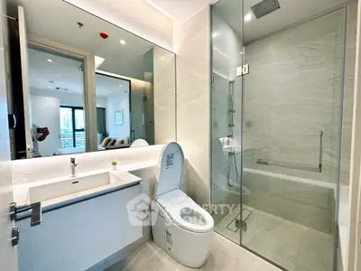 Modern bathroom with glass shower and sleek fixtures in luxury apartment.