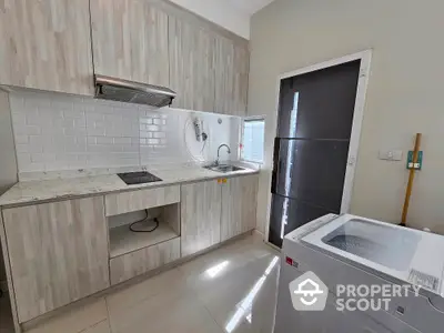 Modern kitchen with sleek cabinetry and washing machine, perfect for urban living.