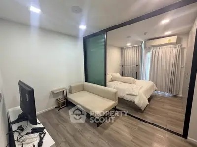 Modern studio apartment with sleek design and cozy bedroom separated by glass partition.