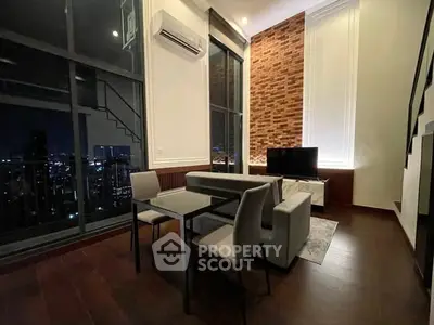 Modern living room with city view, featuring stylish furniture and brick accent wall.