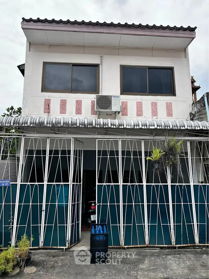 Charming two-story house with unique facade and secure gated entrance, perfect for modern living.