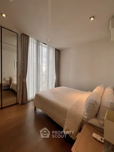 Spacious modern bedroom with large windows and elegant decor in a high-rise apartment.