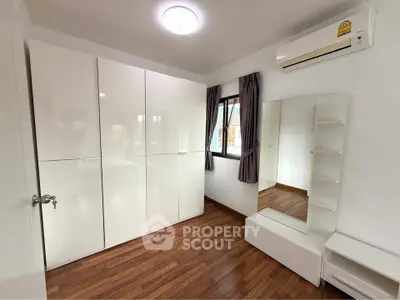 Modern bedroom with sleek white wardrobe and air conditioning