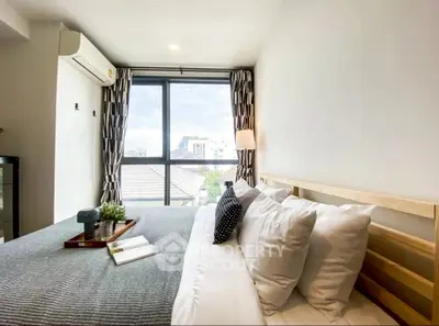 Modern bedroom with large window and stylish decor in urban apartment.