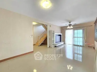 Spacious living room with natural light and modern staircase in a stylish home.