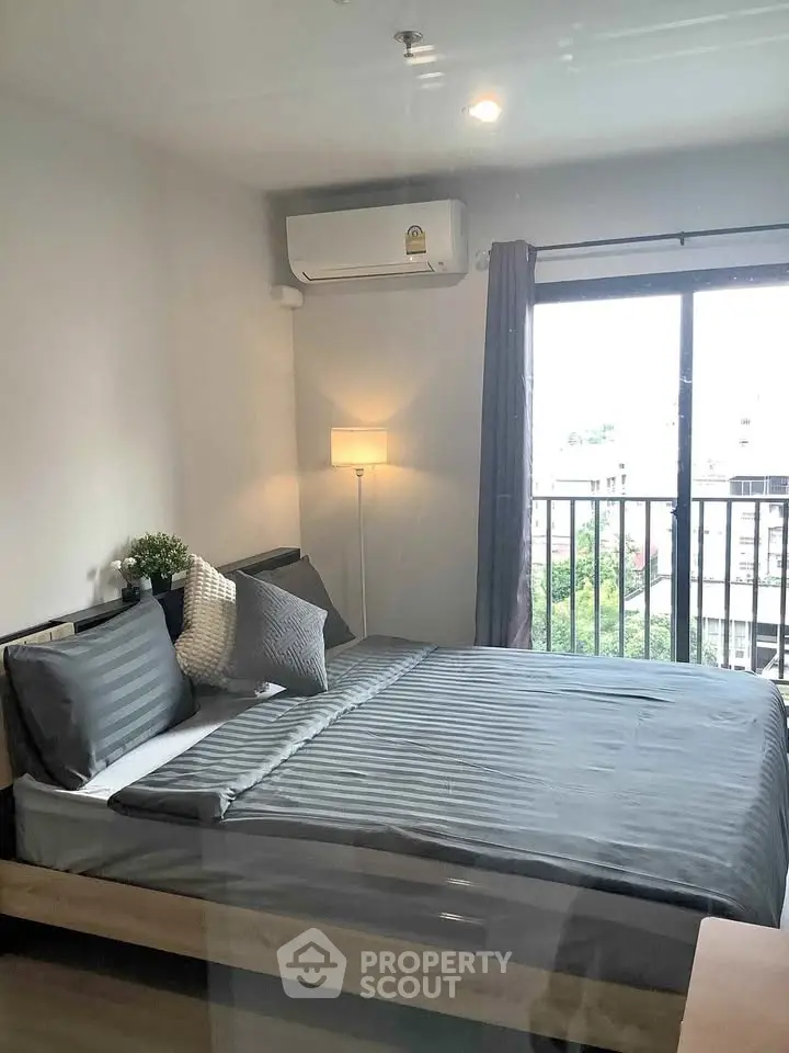 Modern bedroom with balcony view and stylish decor in urban apartment.