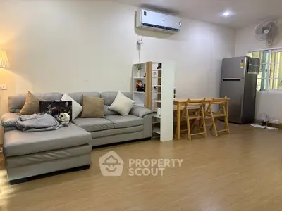 Spacious living room with modern furniture and dining area, featuring air conditioning and wooden flooring.