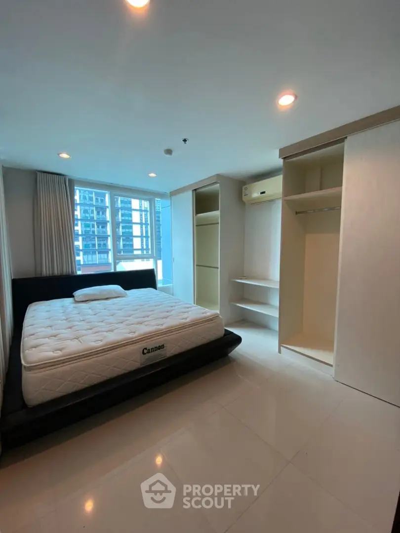 Spacious bedroom with modern design and city view, featuring built-in wardrobe and cozy bed.