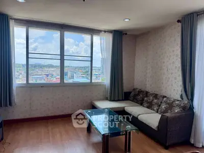 Spacious living room with large windows offering a stunning city view, modern furniture, and elegant decor.