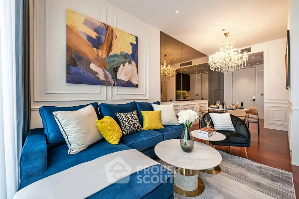 Luxurious living room with elegant decor, plush blue sofa, and modern chandelier lighting.