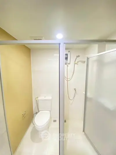 Modern bathroom with shower and toilet in sleek minimalist design.