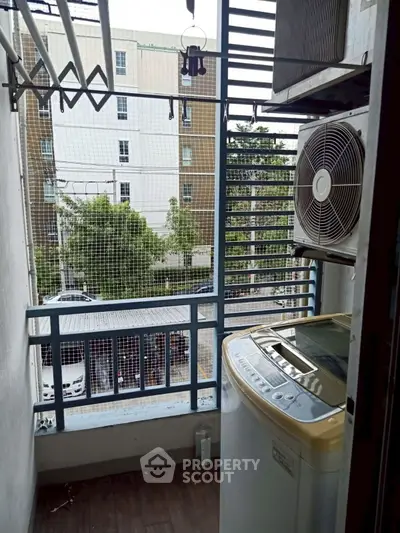 Compact balcony with washing machine and city view, ideal for urban living.