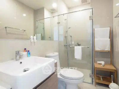 Modern bathroom with glass shower and sleek fixtures in contemporary home.
