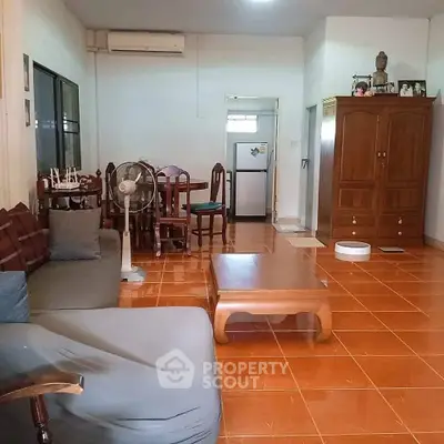 Spacious living room with traditional wooden furniture and tiled flooring, featuring a cozy seating area and dining space.