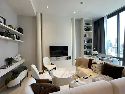 Luxurious modern living room with city view, elegant furniture, and built-in shelves.
