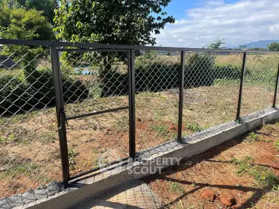 Sturdy metal fence with gate in a sunny garden setting