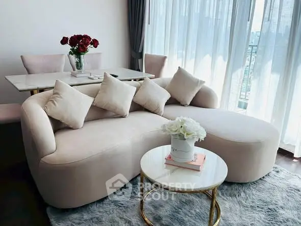 Elegant living room with plush sofa, chic decor, and natural light from large windows.