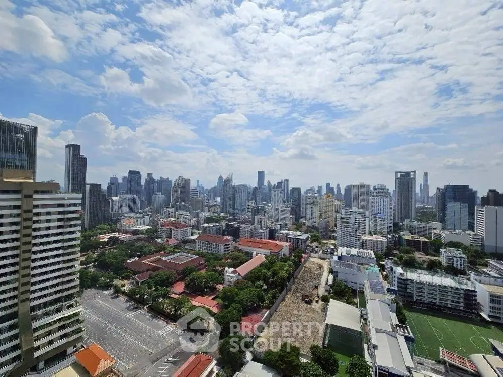 Stunning cityscape view from a high-rise building showcasing urban skyline under a vibrant blue sky.