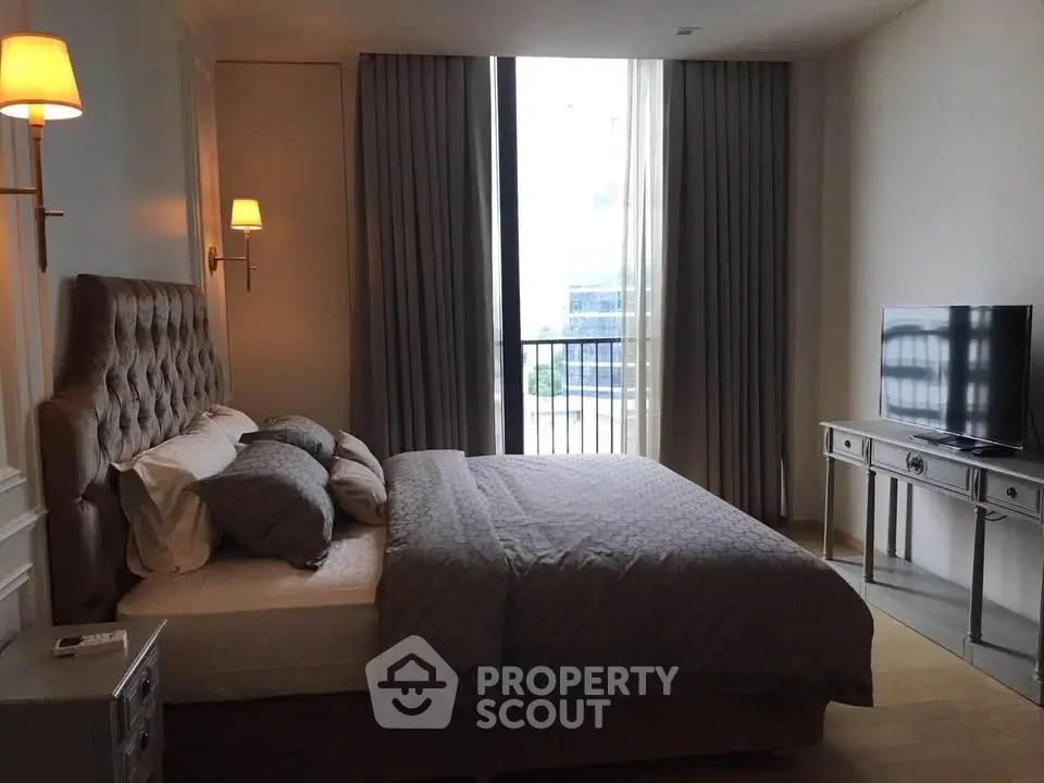 Luxurious bedroom with elegant decor and natural light, featuring a plush bed and modern TV setup.
