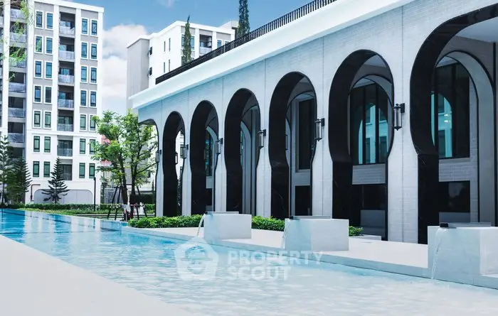 Luxurious modern building with elegant arches and a serene poolside view.