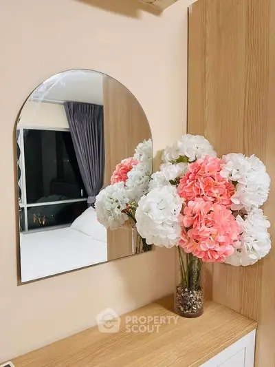Elegant bedroom with stylish mirror and floral decor, showcasing modern interior design.