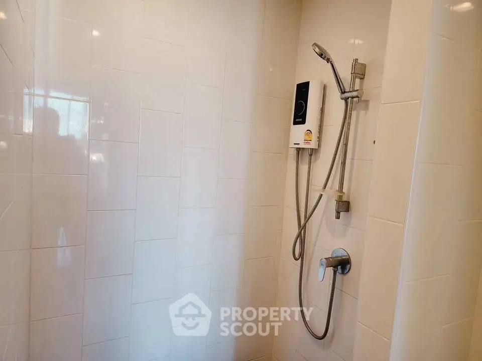 Modern bathroom shower with sleek white tiles and high-quality fixtures.