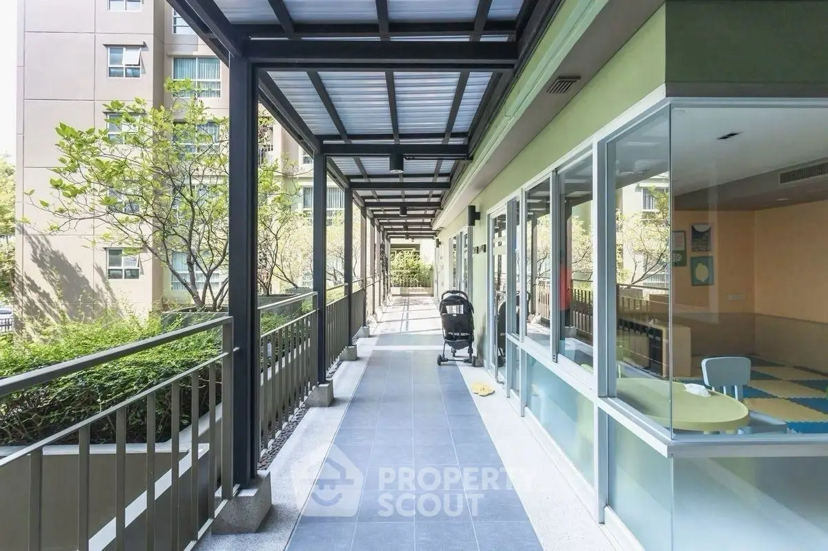 Modern apartment building corridor with glass walls and greenery view.