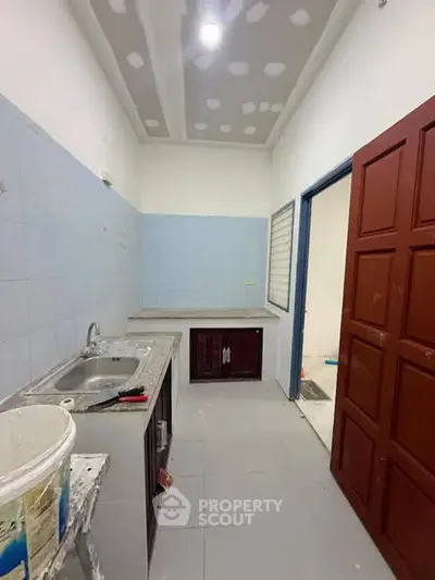 Compact kitchen with tiled walls and basic fixtures, ideal for small apartments.