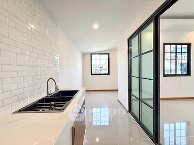 Modern kitchen with sleek design and open layout, featuring a stylish sink and large windows for natural light.