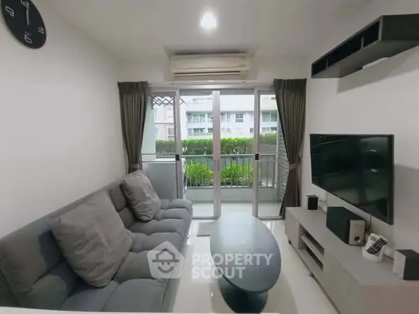 Modern living room with balcony view, featuring sleek furniture and natural light.