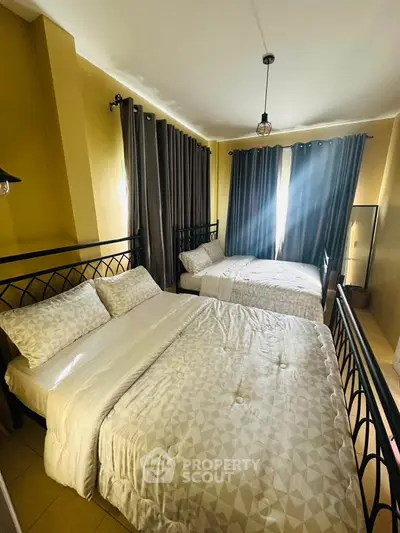 Cozy bedroom with two beds and natural light, perfect for relaxation.