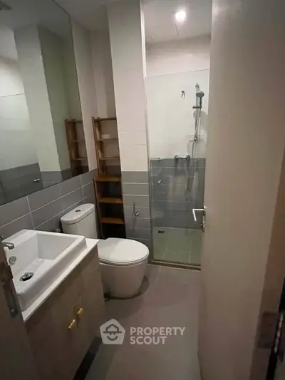 Modern bathroom with sleek design, featuring a glass shower enclosure and contemporary fixtures.
