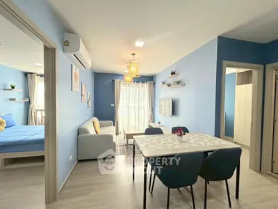 Modern open-plan living room with dining area and bedroom, featuring stylish decor and natural light.