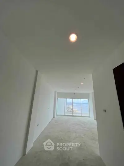 Spacious empty room with large windows offering stunning sea view, perfect for customization.