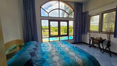 Spacious bedroom with large windows offering stunning pool and garden views, perfect for relaxation.