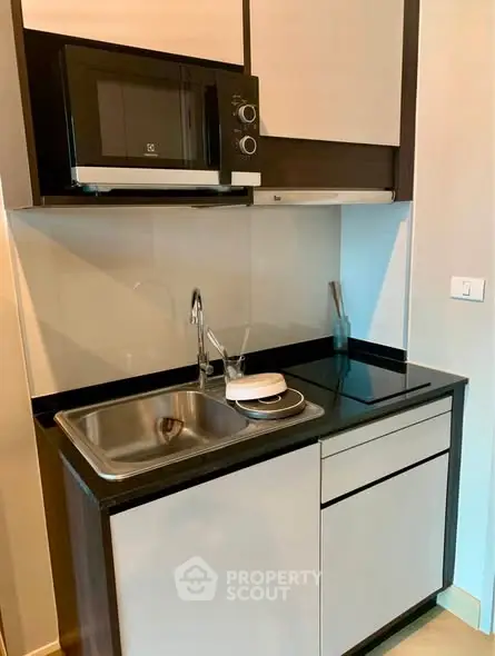 Modern compact kitchen with sleek cabinetry and built-in microwave, ideal for urban living.