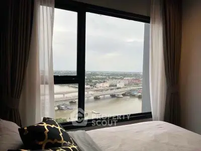 Luxurious bedroom with stunning river view through large window, elegant curtains and stylish decor.