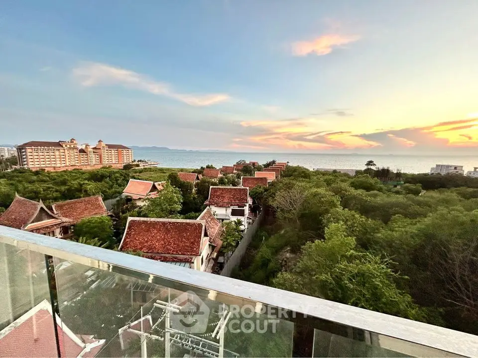 Stunning ocean view from a high-rise balcony overlooking lush greenery and traditional architecture.