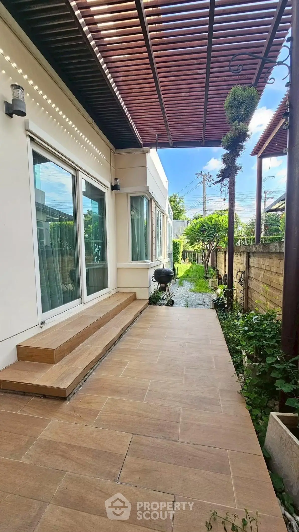 Charming outdoor patio with wooden deck and lush garden view, perfect for relaxation and entertaining.