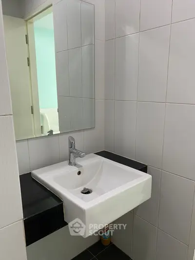 Modern bathroom with sleek white sink and mirror, ideal for contemporary living spaces.