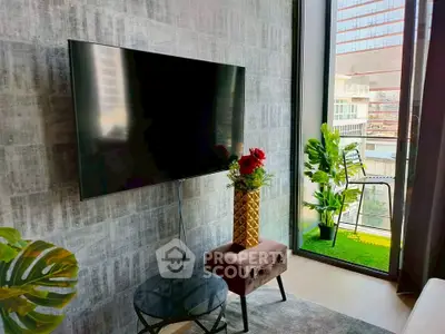 Modern living room with large TV and balcony view in urban apartment.
