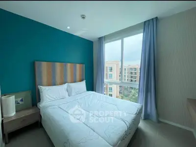 Modern bedroom with large window and stylish decor in urban apartment.