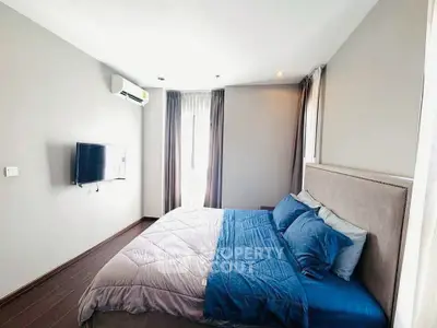 Modern bedroom with cozy bedding and wall-mounted TV in a stylish apartment.